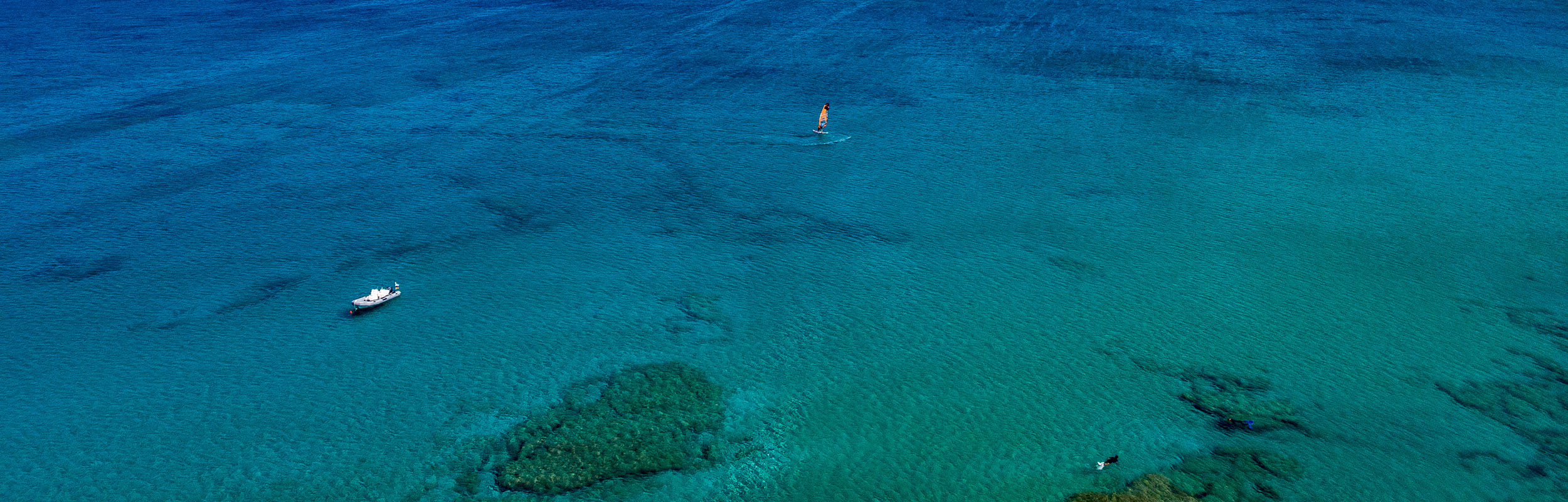 Mediterranean Sea  off the coast of Greece with crystal clear blue water and active wind surfer